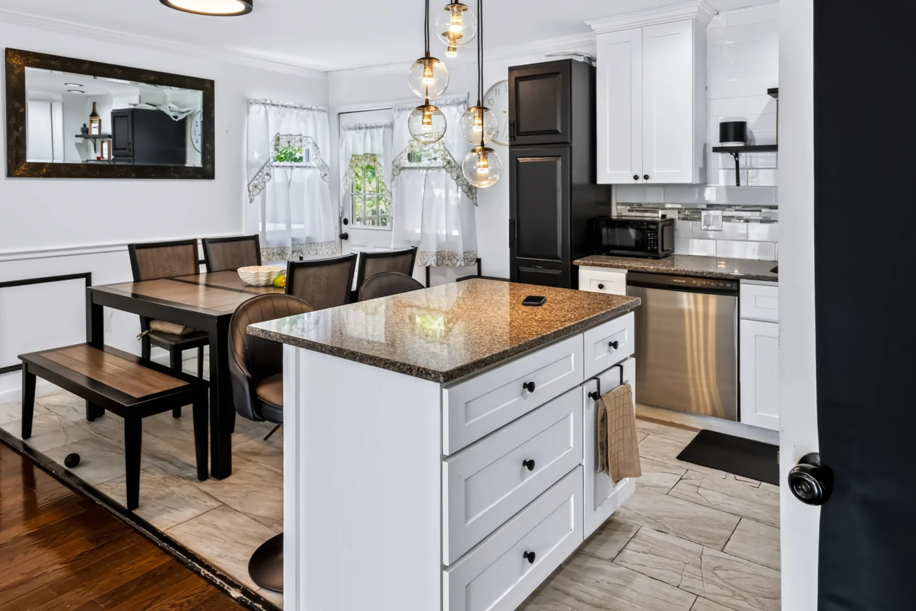 A light-filled kitchen and dining space with white cabinetry and warm wood floors
