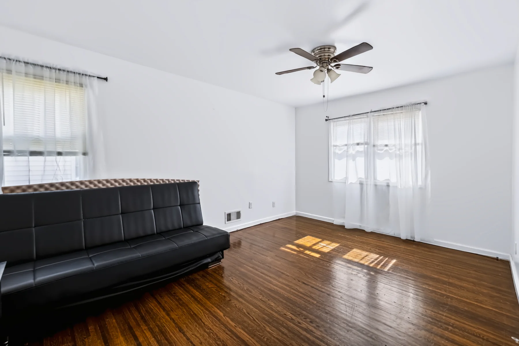 Sunlight falling across hardwood flooring in a room with large windows